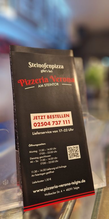 Schwarzes Werbeplakat für einen Pizza-Lieferdienst mit Kontaktdaten und QR-Code.