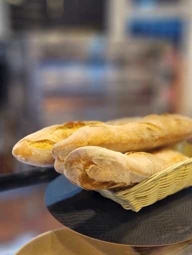 Zwei frische Baguettes auf einem schwarzen Teller.