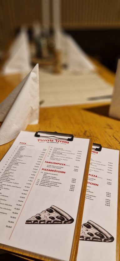 Speisekarten auf einem Holztisch, unscharfer Hintergrund mit weiteren Menüs.